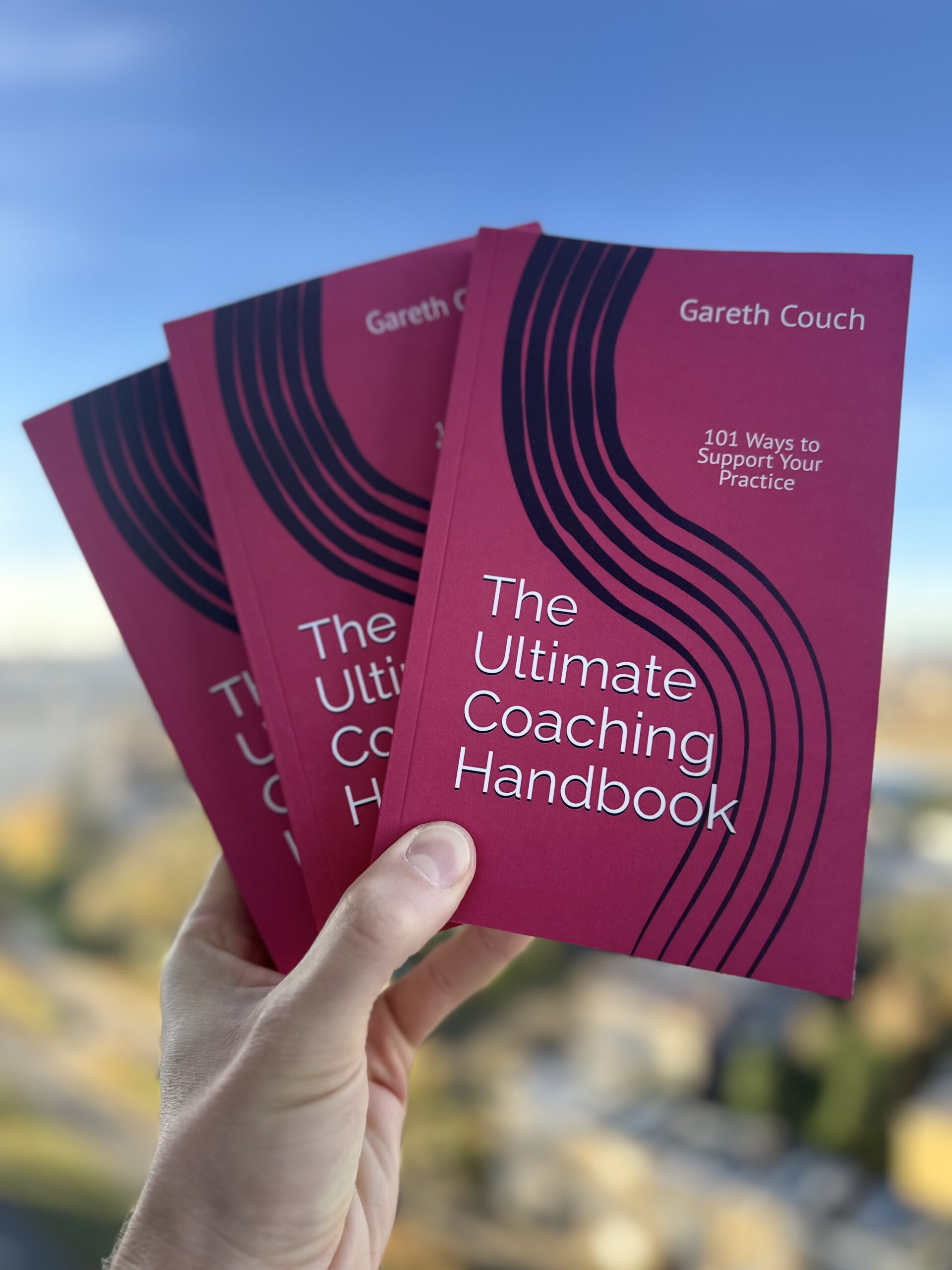 Three copies of The Ultimate Coaching Handbook held in Gareth Couch's hand